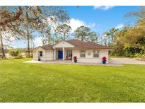 Charming single-story home with a blue front door, manicured lawn, and mature trees at 30041 Redoak Ave, Eustis, FL 32736