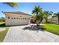 Charming home with a clay tile roof, lush landscaping, and a brick paved driveway leading to a two-car garage at 3403 Great Pond Dr, Kissimmee, FL 34746