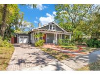 Charming bungalow with a brick driveway, mature landscaping, and inviting front porch at 647 E Livingston St, Orlando, FL 32803