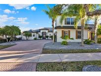 Beautiful two-story home featuring a brick driveway and lush landscaping with palm trees at 2680 Lookout Ln, Kissimmee, FL 34746