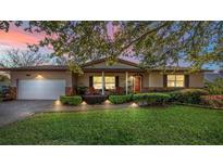 Charming single-story home with lush landscaping, a brick driveway, and a cozy front porch at dusk at 5011 Dorian Ave, Belle Isle, FL 32812