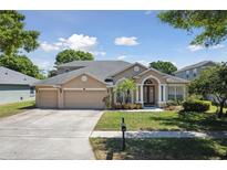 Charming single Gathering home featuring a three-car garage, manicured lawn, and inviting entrance at 5619 Bear Stone Run, Oviedo, FL 32765