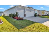 Light blue home featuring a two-car garage, beautiful landscaping, and manicured green lawn at 7369 Sw 77Th Ave, Ocala, FL 34481