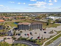 Wide aerial shot of a building with a parking lot, pond, and landscaping at 831 Retreat Blvd # 103, Davenport, FL 33897