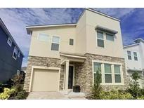 Stylish two-story home showcasing stone accents, neutral stucco, and a convenient attached garage at 9033 Flamingo Key Way, Kissimmee, FL 34747