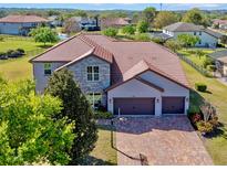 Stunning two-story home showcasing a brick driveway, three car garage, stone accents, and tile roof at 14823 Borromini St, Montverde, FL 34756