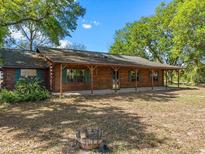 Charming log cabin home featuring a covered front porch and lush landscaping at 16510 Quarter Horse Ct, Montverde, FL 34756