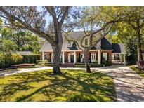 Beautiful brick home with mature trees, circular driveway, and a welcoming front porch; a classic and elegant residence at 1911 Stonehurst Rd, Winter Park, FL 32789