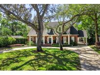Charming traditional home with a manicured lawn, mature trees, and a welcoming front porch with columns at 1911 Stonehurst Rd, Winter Park, FL 32789