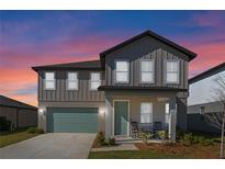 Charming two-story home with gray siding, a covered porch, and a well-maintained green lawn at dusk at 2342 Gold Dust Dr, Minneola, FL 34715