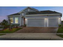 Charming exterior view of a single-Gathering home featuring a two-car garage and a brick driveway at 417 Ironside Trail Dr, Groveland, FL 34736