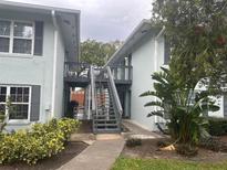 Light blue exterior of a multi-Gathering dwelling with stairs leading to the second floor and tropical landscaping at 4880 S Conway Rd # 85, Orlando, FL 32812