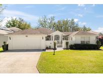 Charming home featuring a well-manicured lawn, white exterior, and a welcoming gated entrance at 5676 Gulf Stream St, Tavares, FL 32778