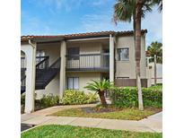 Two story condo building with neutral paint, dark railings, tropical plants, and stairs leading to the second level entrance at 609 Gallery Dr # 2, Winter Park, FL 32792