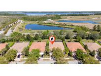 Stunning aerial view of a home near a peaceful pond and lush green surroundings, featuring a terracotta tile roof at 11916 Fiore Dr, Orlando, FL 32827