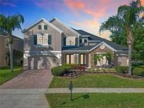A two-story home with brick driveway and manicured lawn, bathed in the warm glow of sunset at 1421 Arbitus Cir, Oviedo, FL 32765
