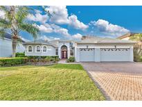 Charming single-story home featuring a three-car garage, red door, manicured lawn, and beautiful landscaping at 1510 Wescott Loop, Winter Springs, FL 32708