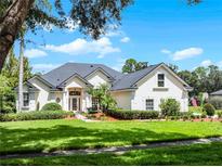 Charming one-story home featuring a beautifully landscaped yard, vibrant green lawn and a pristine white stucco exterior at 2544 Carter Grove Cir, Windermere, FL 34786