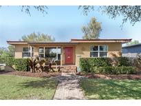 Charming single-story home with a red door, lush landscaping, and a brick pathway leading to the entrance at 3803 Bobolink Ln, Orlando, FL 32803