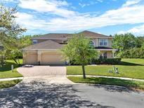 Beautiful two-story home featuring a three-car garage, manicured lawn, and a brick-paved driveway at 4393 S Devon Ct, Kissimmee, FL 34746