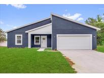 Modern home featuring a blue exterior, white trim, and a well-manicured lawn at 4761 Sw 142Nd Place Rd, Ocala, FL 34473