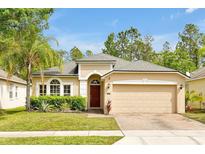 Charming home with a lush green lawn, mature landscaping, and a brick driveway at 9457 Candice Ct, Orlando, FL 32832