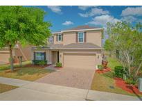 Charming two-story home with a manicured lawn, brick driveway, and attached two-car garage at 1040 Andalusia Loop, Davenport, FL 33837