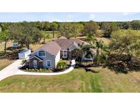 Stunning single-Gathering home featuring lush landscaping, a circular driveway and a charming stone facade at 25249 Derby Dr, Sorrento, FL 32776