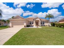 Charming single-story home featuring a well-manicured lawn, beautiful landscaping, and a spacious two-car garage at 2712 Pearl Court, Kissimmee, FL 34743
