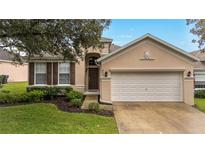 Charming single-story home with manicured lawn, mature tree, and an attached two-car garage at 417 Calabay Parc Blvd, Davenport, FL 33897