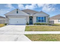 Charming single-story home featuring a two-car garage, well-maintained lawn, and a welcoming front door with wreath at 493 Talisi Loop, St Cloud, FL 34771