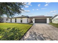 Charming single-story home featuring a modern design, dark trim, two car garage, and a well-manicured front yard at 607 Dunblane Dr, Winter Park, FL 32792