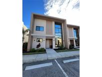 Modern townhome featuring clean architectural lines, a private entrance, and lush landscaping at 7465 Bleecker Ln, Kissimmee, FL 34747