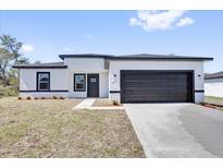 Charming single-story home featuring black trim, a dark garage door and a well-manicured lawn at 13584 Sw 43Rd Cir, Ocala, FL 34473