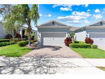 Charming home featuring a well-manicured lawn and a two-car garage, set under a sunny sky with beautiful landscaping at 1830 Estuary Ln, Kissimmee, FL 34747