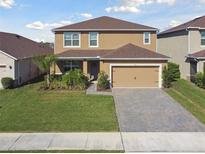 Charming two-story home featuring a well-manicured lawn, paver driveway, and two-car garage in a Gathering-friendly neighborhood at 211 Lazio Cir, Debary, FL 32713