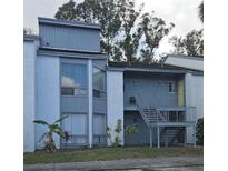 Exterior view of a two-story condo building featuring light blue siding, a shared staircase, and a small front yard at 2432 Lemon Tree Ln # B, Orlando, FL 32839