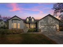 Charming home featuring white siding, stone accents, and a well-manicured lawn against a twilight sky at 1667 Spring Loop Way, Winter Garden, FL 34787