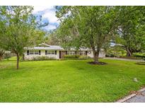 Charming single-story home features a well-maintained front yard with mature trees and manicured landscaping at 1800 Johnson Dr, Clermont, FL 34711