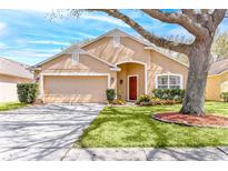 Charming single-story home with a well-manicured lawn, mature tree, and inviting red door at 2109 Carpathian Dr, Apopka, FL 32712