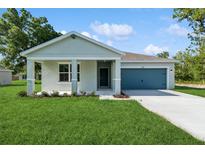 Charming single-story house with manicured lawn, a blue front door and a blue garage door at 8651 Sw 138Th St # 68, Ocala, FL 34473