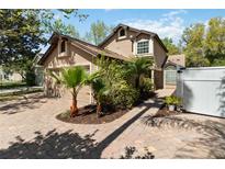 Charming home with a two car garage, brick driveway, and lush tropical landscaping at 9939 Triple Crown Cir, Orlando, FL 32825