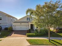 Charming single-Gathering home featuring a well-manicured lawn, brick driveway, and a two-car garage at 10018 Halesia Woods Dr, Orlando, FL 32832