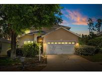 Charming single-Gathering home with a well-manicured lawn and an attached two-car garage at dusk at 229 Troon Cir, Davenport, FL 33897