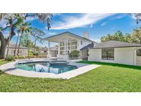 This backyard features a sparkling pool and spa, surrounded by lush greenery and a patio area at 409 W 2Nd Ave, Windermere, FL 34786