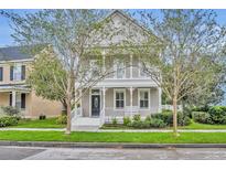 Charming two-story home with front porch and balcony, framed by mature trees and a well-manicured lawn at 5492 Penway Dr, Orlando, FL 32814