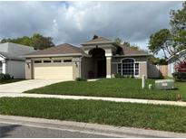 Charming single-story home with a well-manicured lawn, neutral stucco, attached two-car garage, and arched front entryway at 10536 Cherry Oak Cir, Orlando, FL 32817