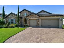 Beautiful stone home featuring a three-car garage and a meticulously maintained front yard at 16736 Broadwater Ave, Winter Garden, FL 34787