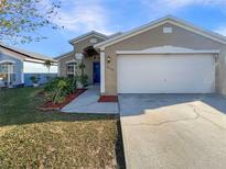 Charming home featuring a blue door, a two-car garage, and landscaped front yard with colorful plants at 2350 Blue Sapphire Cir, Orlando, FL 32837