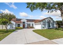 Charming single-story home features a well-manicured lawn, a concrete driveway, and solar panels for energy efficiency at 2821 Lone Feather Dr, Orlando, FL 32837